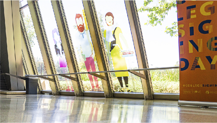 Vinyl stickers of illustrated students displayed on windows in concourse