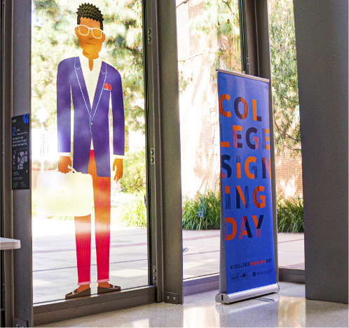 Vinyl sticker on window of student character with a banner next to it with CSD logo